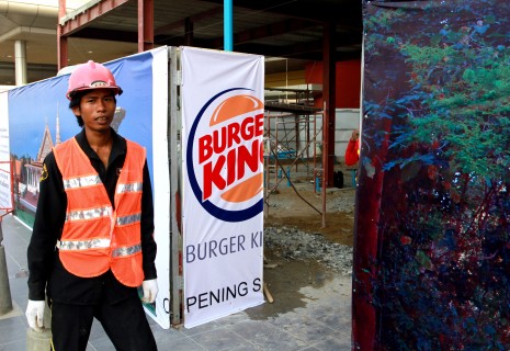 A worker stands beside an advertisement for Burger King at the Phnom Penh International Airport on Thursday. (Siv Channa)
