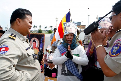 Boeng Kak anti-eviction activist Kong Chantha, center, is flanked by two police officers as she prays for the release of jailed fellow activist Yorm Bopha outside the Royal Palace in Phnom Penh on Friday. (Siv Channa)