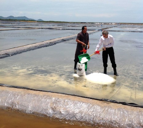 Bun Bariang, left, co-executive director of the Salt Association of Kampot, and Peter Bird, non-executive director of InfraCo Asia, shovel sea salt into a bag on Saturday at the inauguration of a new farm in Kampot province. (Simon Lewis/The Cambodia Daily)
