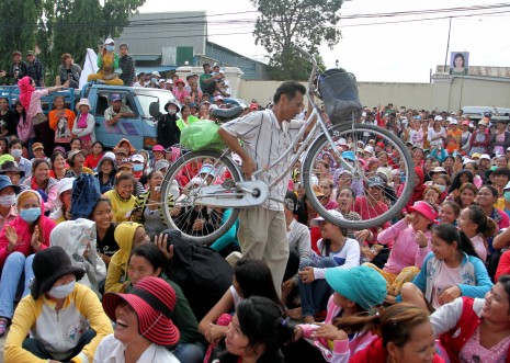 National Road 2 Blocked by 2,000 Protesters 1 A man carries his bicycle through a 2,000-strong crowd of protesting garment factory workers who blocked National Road 2 in Phnom Penh on Wednesday to demand better pay and work conditions. The workers, who make clothes for Swedish clothes brand H&M, stopped traffic for about 90 minutes. (Siv Channa)