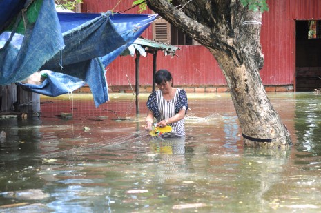 A resident in Phnom Penh's Khva village wades through water near her home on Wednesday. (Simon Henderson/ The Cambodia Daily)