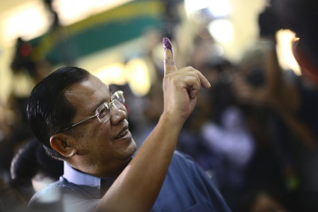 Prime Minister Hun Sen holds up his inked finger after voting Sunday morning at Kandal Provincial Teachers Training Center in Takhmao City. (Lauren Crothers/Cambodia Daily)