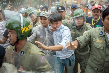 Riot police lead a man to safety after he was attacked by angry voters and monks who had complained of being unable to find their names on the official voter list in Phnom Penh's Meanchey district. (Thomas Cristofoletti)