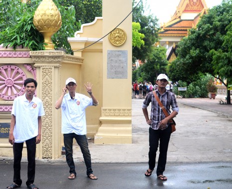 A youth at Wat Botum pagoda in Phnom Penh on Thursday, dressed in a CPP T-shirt and a cap, raises four fingers to represent the numerical placement on the July 28 ballot papers of Prime Minister Hun Sen's ruling party. (Simon Henderson/The Cambodia Daily)