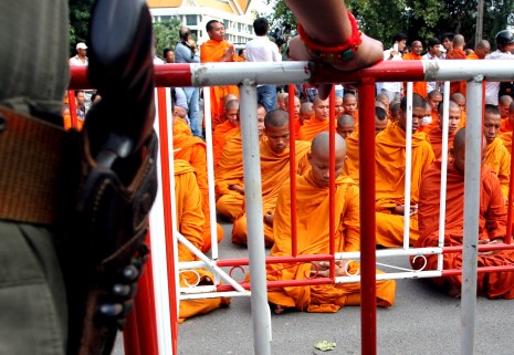 Monks on Phnom Penh's Sisowath Quay meditate behind barricades manned by armed police officers on Thursday. The blockades were set up to prevent the monks from reaching the Royal Palace, where they planned to pray for King Norodom Sihamoni to reconsider his decision to convene the National Assembly on Monday. (Siv Channa)