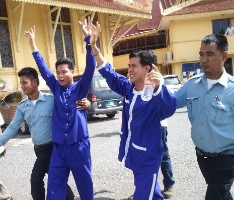 With arms raised in triumph, Sok Sam Oeun, left, and Born Samnang, who were sentenced to 20 years jail for the murder of union leader Chea Vichea in 2004, leave the Supreme Court in Phnom Penh after being acquitted due to a lack evidence. (Nhim Sokhorn)