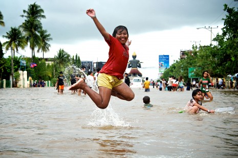 A young girl jumps in the air in a badly flooded area of Battambang City on Sunday. Many provinces have been hit by flooding in the past two weeks. (Shathel Fahs)