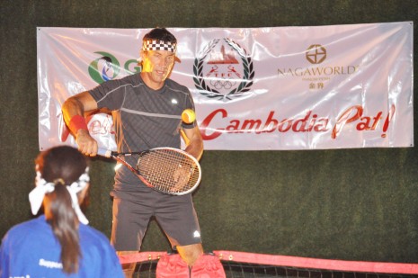 Wimbledon champion Pat Cash plays a practice game with a young Cambodian tennis player. (Simon Henderson)