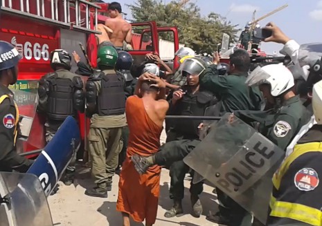 A police officer kicks a monk from Stung Meanchey pagoda after several monks were rounded up and detained following clashes in the area on Tuesday. (Licadho) 