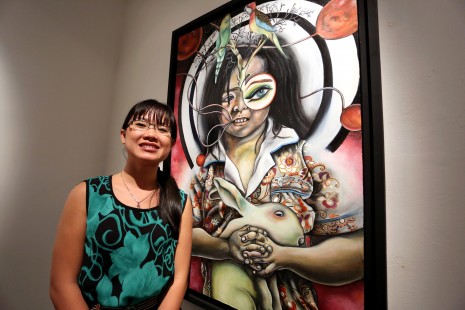 Oeur Sokuntevy's stands next to her painting 'Parakeets.' (Siv Channa)