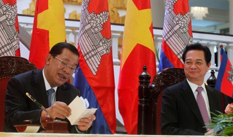 Prime Minister Hun Sen, left, reads his schedule while chatting with his Vietnamese counterpart, Nguyen Tan Dung, in Hanoi on Thursday. (Reuters)