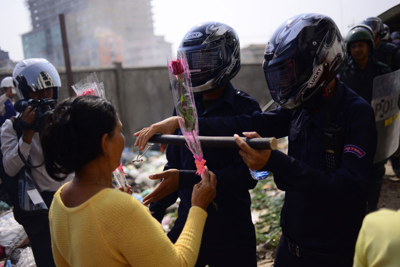 Borei Keila resident So Im offers flowers to Prampi Makara district security officers on Friday after police evicted villagers from a building site they were occupying, injuring at least six people. (Lauren Crothers/The Cambodia Daily)