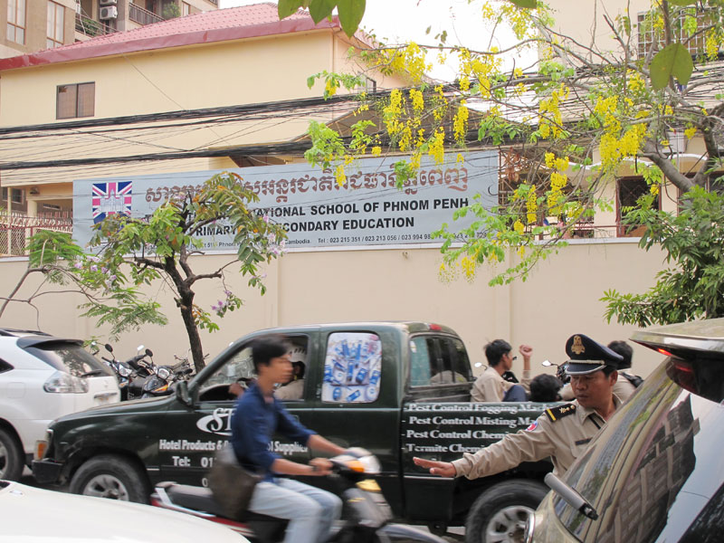A police officer directs traffic outside the British International School of Phnom Penh as parents flock to pick up their children after school on Friday. (Emily Wilkins)