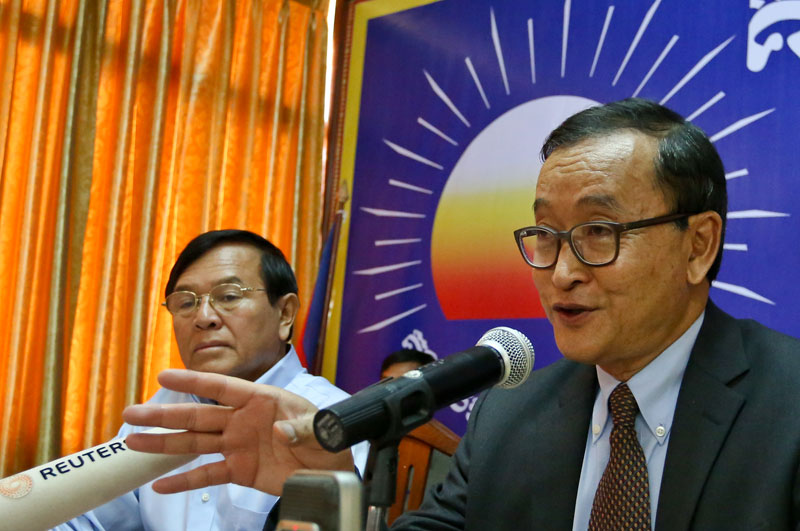 CNRP President Sam Rainsy, seated alongside Vice President Kem Sokha, speaks during a press conference at the party headquarters on Wednesday. (Siv Channa)