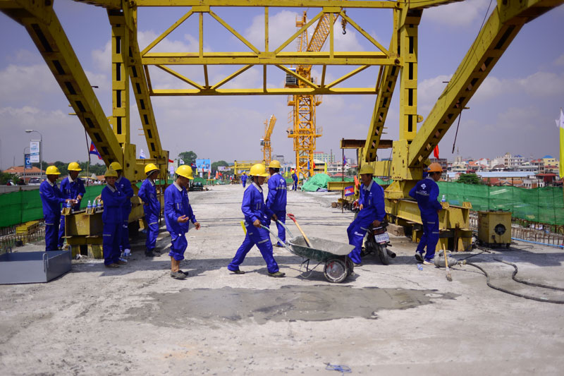 Workers from the China Road and Bridge Corporation on Wednesday connect the two sides of a $27.5 million Chinese-funded bridge across the Tonle Sap river. (Lauren Crothers/The Cambodia Daily)