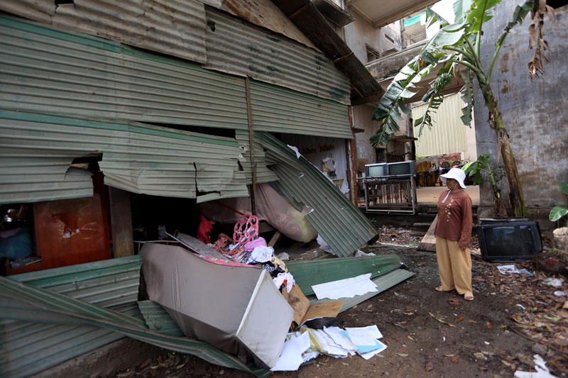 A woman surveys damage done to a house in Tuol Kok district by over a dozen men wielding wooden sticks and swords on Sunday morning. The house's inhabitants are at the center of a long-running land dispute with businessman Khun Sear. (Siv Channa)