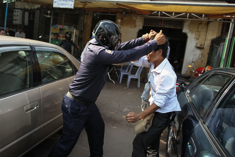 A Daun Penh district security guard prepares to knee a man in the face Monday on a street adjacent to Phnom Penh's Freedom Park. (Ishikawa Masayori)