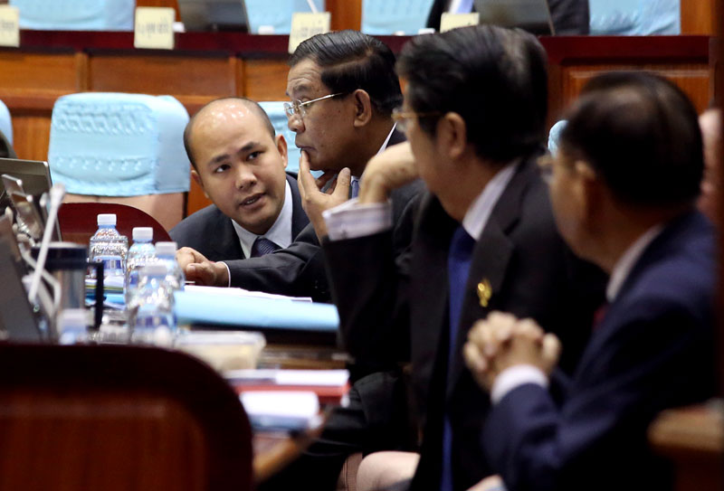 CPP lawmaker Hun Many confers with his father, Prime Minister Hun Sen, as deputy prime ministers Sok An, second from right, and Keat Chhon look on. The CPP-only National Assembly on Tuesday convened its second session since a new government was formed in September. (Siv Channa)