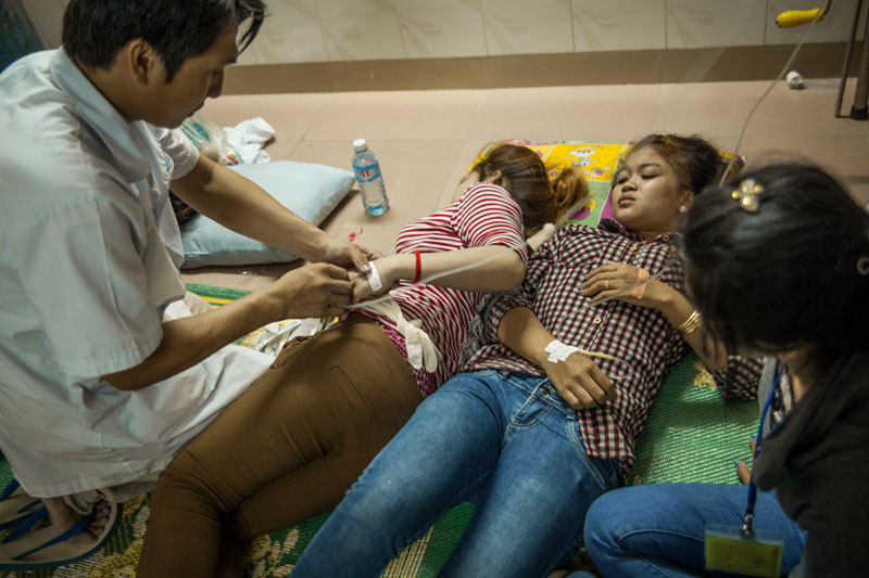 A doctor at the Ekreach Clinic in Phnom Penh's Pur Senchey district tends to employees of the Shenzhou garment factory, where 118 workers fainted Thursday morning. (Heather Stilwell)