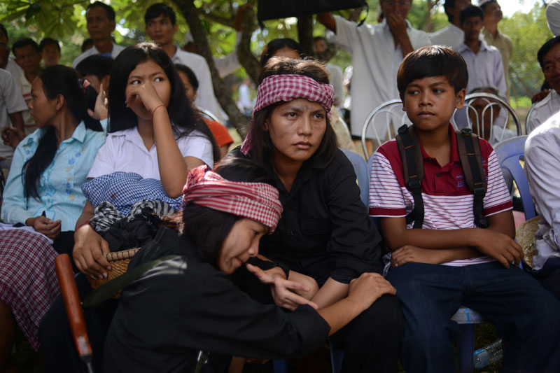 Two actresses dressed in Khmer Rouge-style clothes listen to a speech during the annual 'Day of Anger' ceremony at the Choeung Ek Genocidal Center in Phnom Penh on Tuesday. (Lauren Crothers/The Cambodia Daily) 