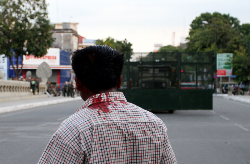 A man looks back at a secured area of Norodom Boulevard, on the east flank of Freedom Park, after being beaten by Daun Penh district security guards during a suppressed CNRP campaign gathering in Phnom Penh Friday afternoon. (Siv Channa)