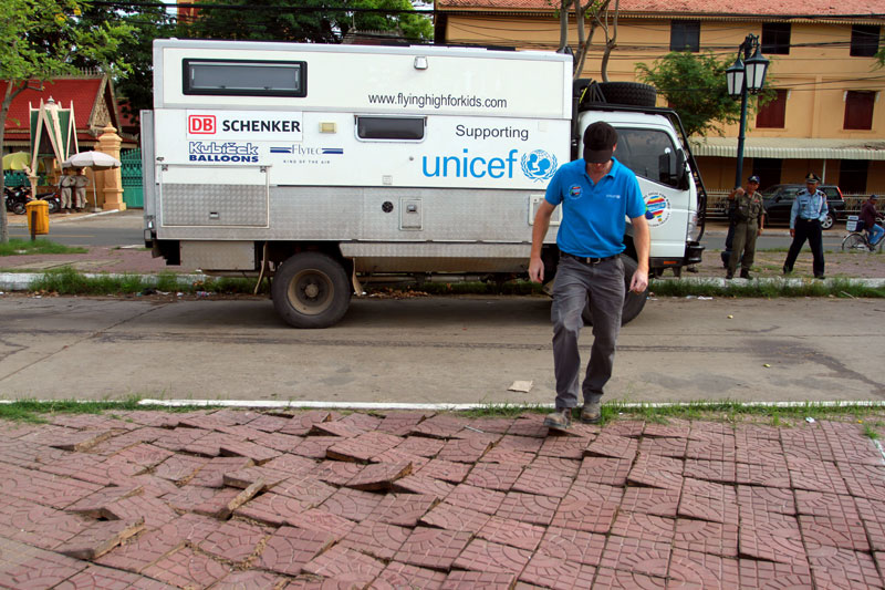 Andrew Parker, pilot of a hot air balloon raising funds for Unicef, walks over tiles dislodged by a truck he drove across Phnom Penh's Wat Botum Park. (Siv Channa/The Cambodia Daily)