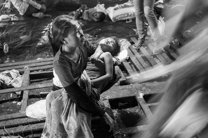 A woman carries her daughter on her lap after getting off the truck at the Poipet international checkpoint. (John Vink)