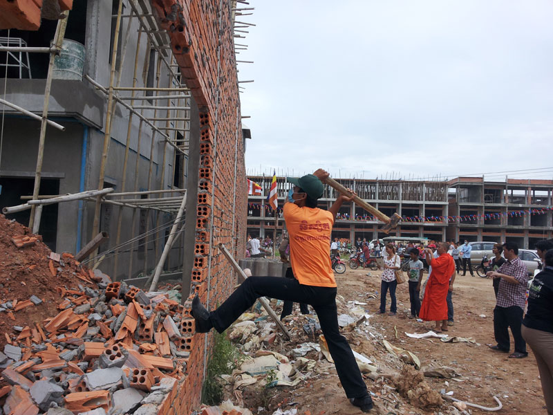 A protester uses a sledgehammer to destroy a wall on disputed land in Phnom Penh's Sen Sok district on Sunday. (Mech Dara/The Cambodia Daily)