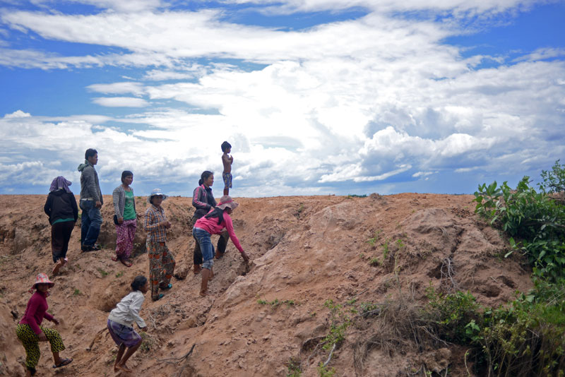 Lor Peang villagers clamber up the bank of a creek that demarcates the boundary of a disputed 145-hectare plot of land in Kompong Chhnang province on Monday, which they say the KDC company illegally grabbed from them in 2002. (Lauren Crothers/The Cambodia Daily)