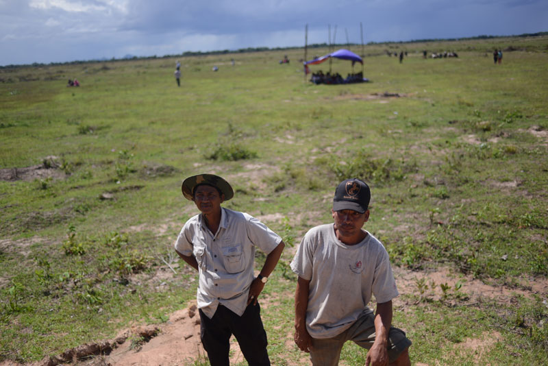 KDC workers waited for instructions from their superiors to continue clearing land and flattening the bank to erect a wall around the disputed site. (Lauren Crothers/The Cambodia Daily)