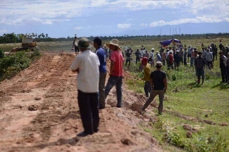 By about 3 p.m., a tractor began moving earth and flattening the bank that villagers had earlier climbed up. More than an hour later, villagers and workers clashed again. (Lauren Crothers/The Cambodia Daily)