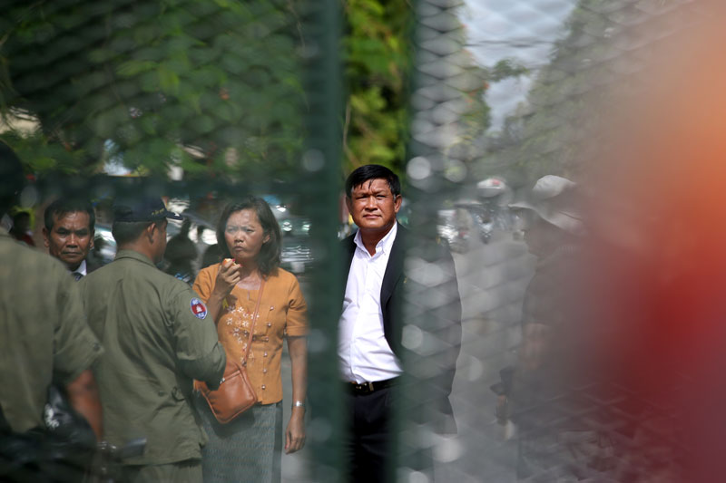 From left, opposition CNRP lawmaker-elect Men Sothavrin, public affairs chief Mu Sochua and opposition lawmaker-elect Keo Phirum stand behind police barriers after being detained Tuesday near Freedom Park. (Siv Channa/The Cambodia Daily)
