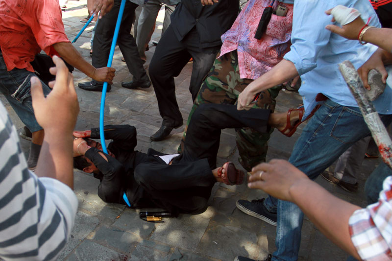 A security guard is beaten by opposition CNRP protesters Tuesday near Freedom Park. (Siv Channa/The Cambodia Daily)