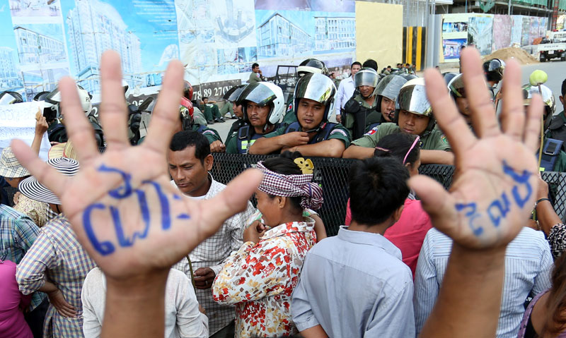 An opposition supporter holds up his hands—marked with the message 'release'—in front of a police barricade blocking off Phnom Penh Municipal Court, where six CNRP officials were questioned and charged Wednesday with insurrection and incitement to commit a felony for their alleged role in a violent protest on Tuesday. (Siv Channa/The Cambodia Daily)