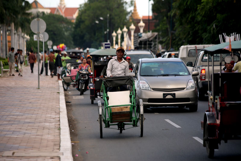 A cyclo driver pedals along the Riverside in front of the Royal Palace on Tuesday. (Siv Channa/The Cambodia Daily)