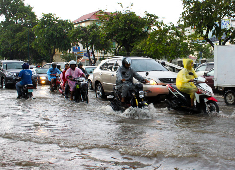 Motorists drive along a flooded stretch of Norodom Boulevard following torrential rains Tuesday afternoon. (Holly Robertson/The Cambodia Daily)