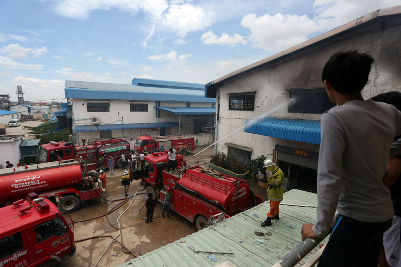 Firefighters attempt to put out a fire Monday morning that completely gutted a garment factory in Phnom Penh's Pur Senchey district, killing a Chinese supervisor. (Siv Channa/The Cambodia Daily)