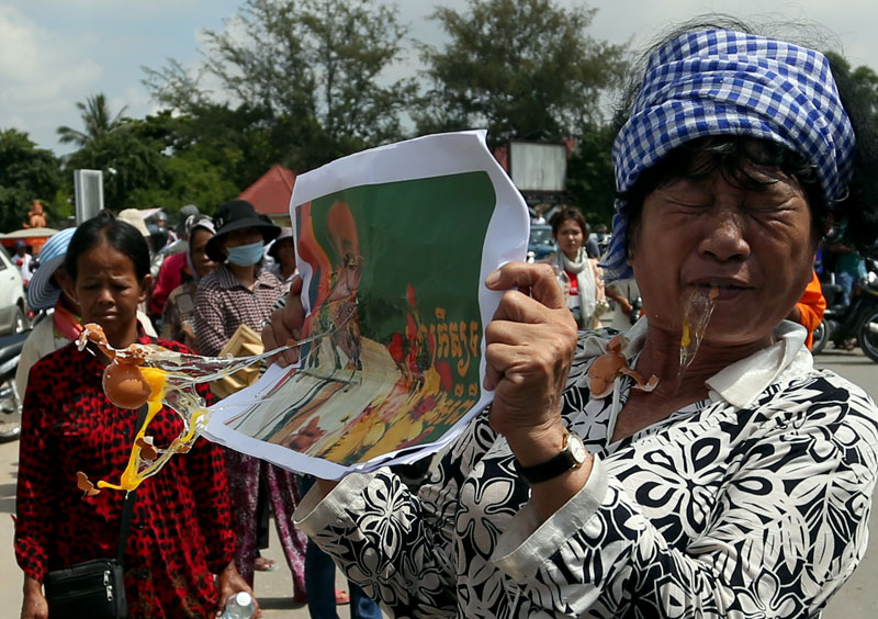 A protester holds up a photograph of former Phnom Penh Governor Kep Chuktema as it is pelted with eggs by fellow protesters near the National Assembly on Wednesday. (Siv Channa/The Cambodia Daily)