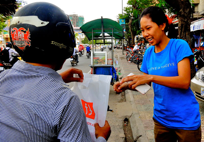 A delivery man drops off a blouse to a customer who made her purchase through Facebook. (Melanie Eng/The Cambodia Daily)