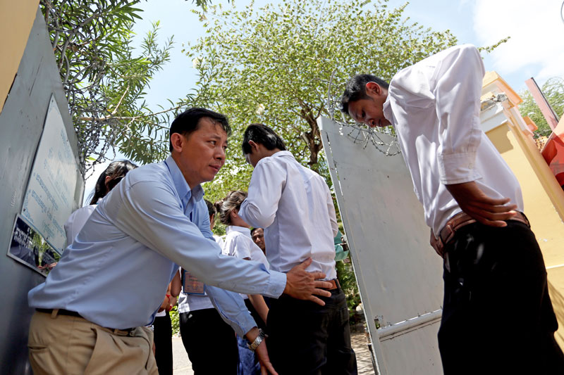 A school official frisks students as they enter Sisowath High School in Phnom Penh ahead of the second session of the grade 12 national exam Monday afternoon. The Ministry of Education has made a priority this year of ridding the exam of corruption and cheating. (Siv Channa/The Cambodia Daily)