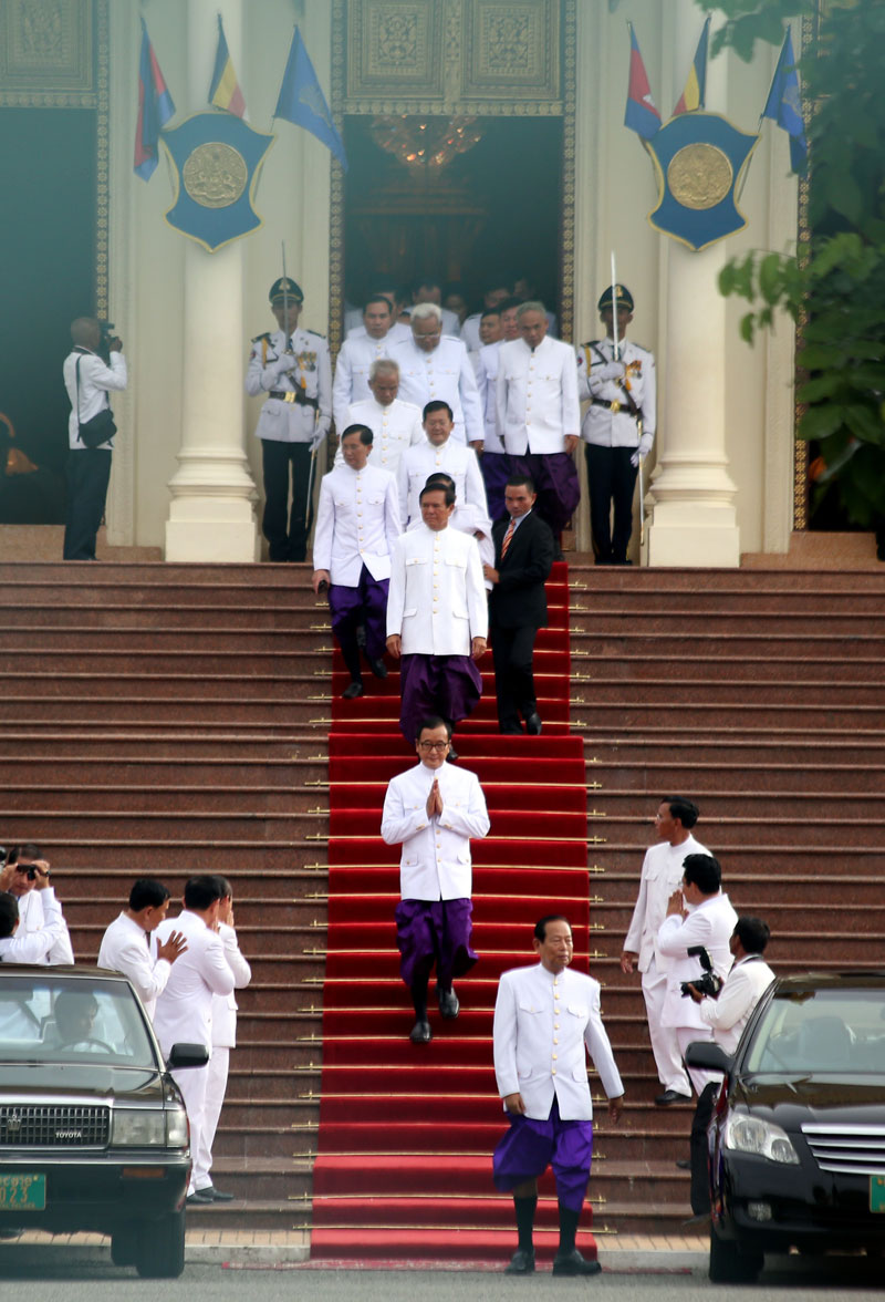 Opposition leader Sam Rainsy, hands together, leads the CNRP's 55 lawmakers out of the Royal Palace on Tuesday afternoon after being sworn in to office by King Norodom Sihamoni. (Siv Channa/The Cambodia Daily)