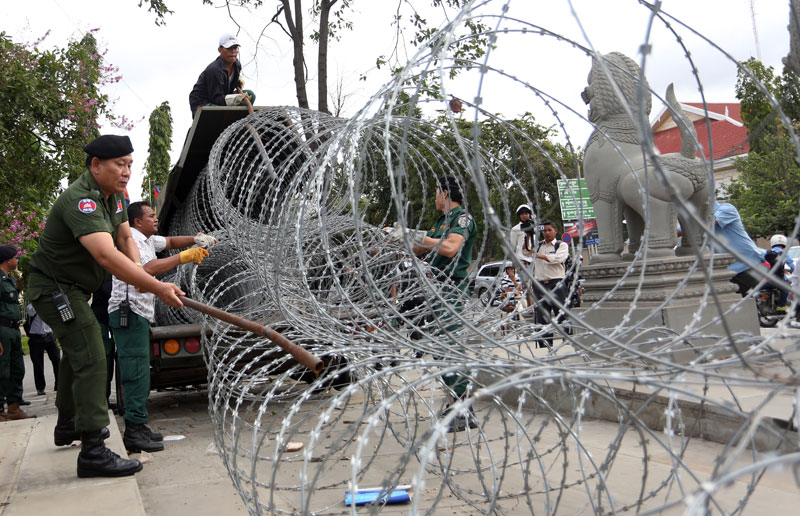 Municipal police on Wednesday remove razor-wire barricades from the fringe of Phnom Penh's Freedom Park, which had been locked down since January after being used for months as a rallying point for mass opposition demonstrations. Authorities said the city's security situation was back to normal after 55 opposition lawmakers were sworn into office on Tuesday following a 10-month boycott of parliament. (Siv Channa/The Cambodia Daily)