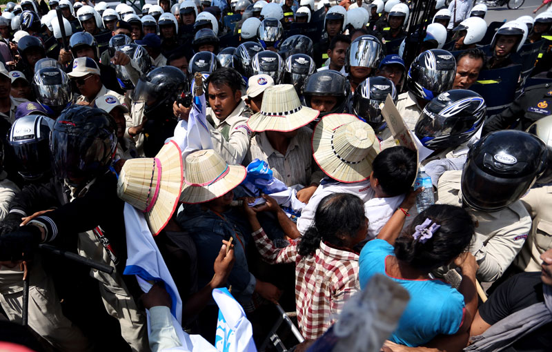 Dozens of district security guards backed by military police surround protesting farmers from Kratie province on Monday at Phnom Penh's Wat Botum park. (Siv Channa/The Cambodia Daily)