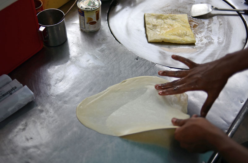 A Rohingya Muslim refugee makes roti at his food cart on Friday. (Lauren Crothers/The Cambodia Daily)