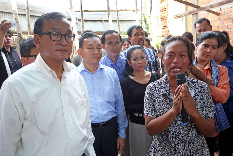 CNRP President Sam Rainsy stands beside Oum Sophy, a representative of residents from Lor Peang village in Kompong Chhnang province, during a gathering Thursday in Phnom Penh. (Siv Channa/The Cambodia Daily)