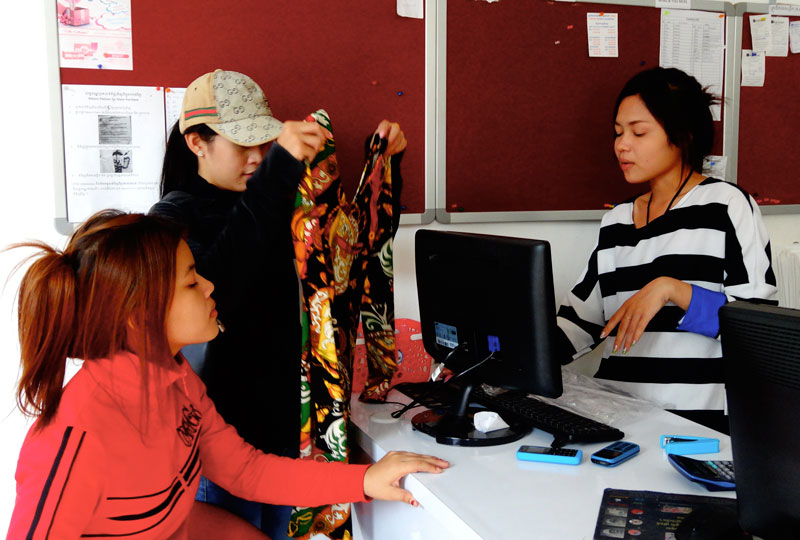 Customers inspect clothing inside a retail outlet that offers purchases via Facebook. (Melanie Eng/The Cambodia Daily)