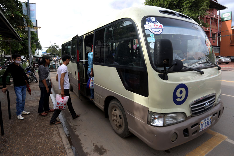 Passengers file onto a bus at a stop on Monivong Boulevard on Monday. (Siv Channa/The Cambodia Daily)