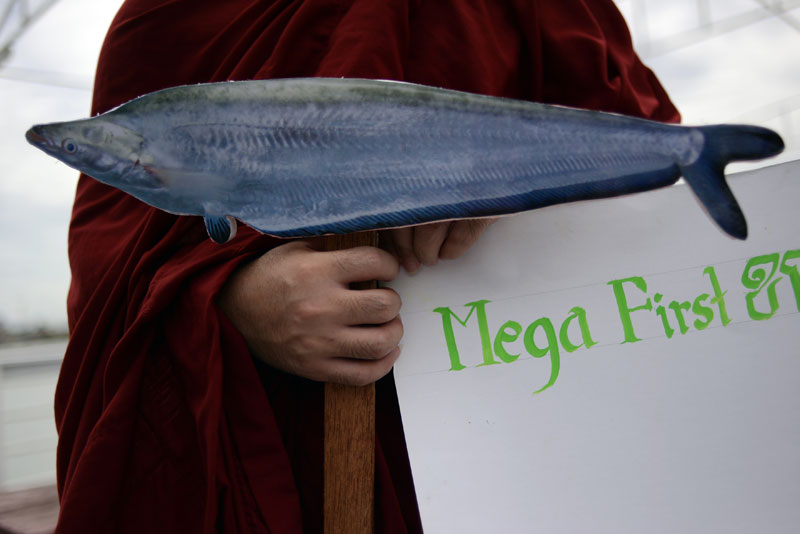 A monk holds a cardboard cut-out of a fish during a demonstration on Thursday in Phnom Penh against the construction of the Don Sahong dam in Laos. (Lauren Crothers/The Cambodia Daily)