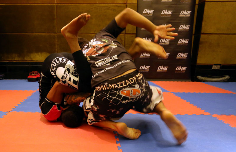 Brazilian mixed martial artist Adriano Moraes grapples with his trainer and manager, Alex Nacfur, at NagaWorld in Phnom Penh on Tuesday. (Siv Channa/The Cambodia Daily) 