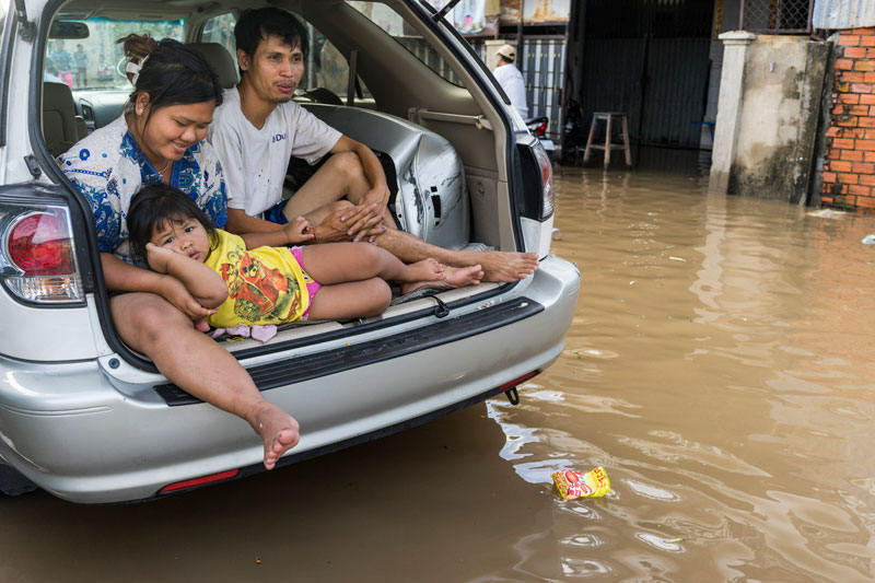 A family stays dry in the trunk of their car parked on a flooded street in Phnom Penh's Boeng Kak neighborhood Sunday. About 60 Boeng Kak residents protested outside City Hall on Sunday, accusing municipal officials of conspiring to prevent water from draining from the area. (John Vink)